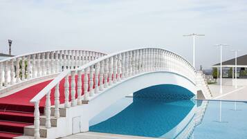 A white bridge with balustrades leading to a pool area.