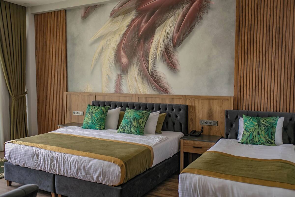 Une chambre d’hôtel avec deux lits, une grande fresque murale, un lambris en bois et une table de chevet avec un téléphone.