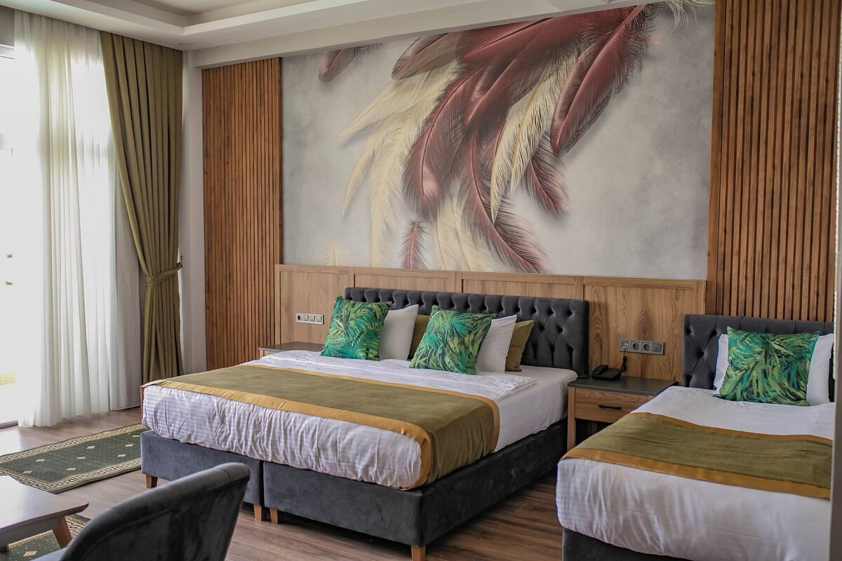 Une chambre d’hôtel avec un grand lit, deux tables de chevet, une chaise et une fresque murale.