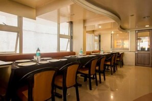 Un salón de conferencias con mesas largas y sillas, equipado con botellas de agua y platos.