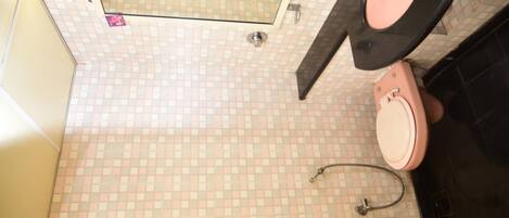 A bathroom with a tiled floor, a toilet, a shower, and a sink.