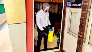 A hotel entrance with a sign reading "HOTEL CELEBRATIONS INN" and a person holding a cleaning tool. - Celebrations Inn (Pune)