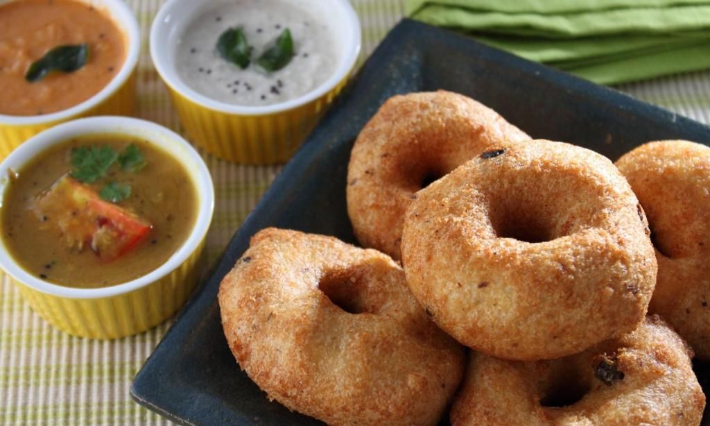 A plate of fried snacks with three small bowls of dipping sauces.
