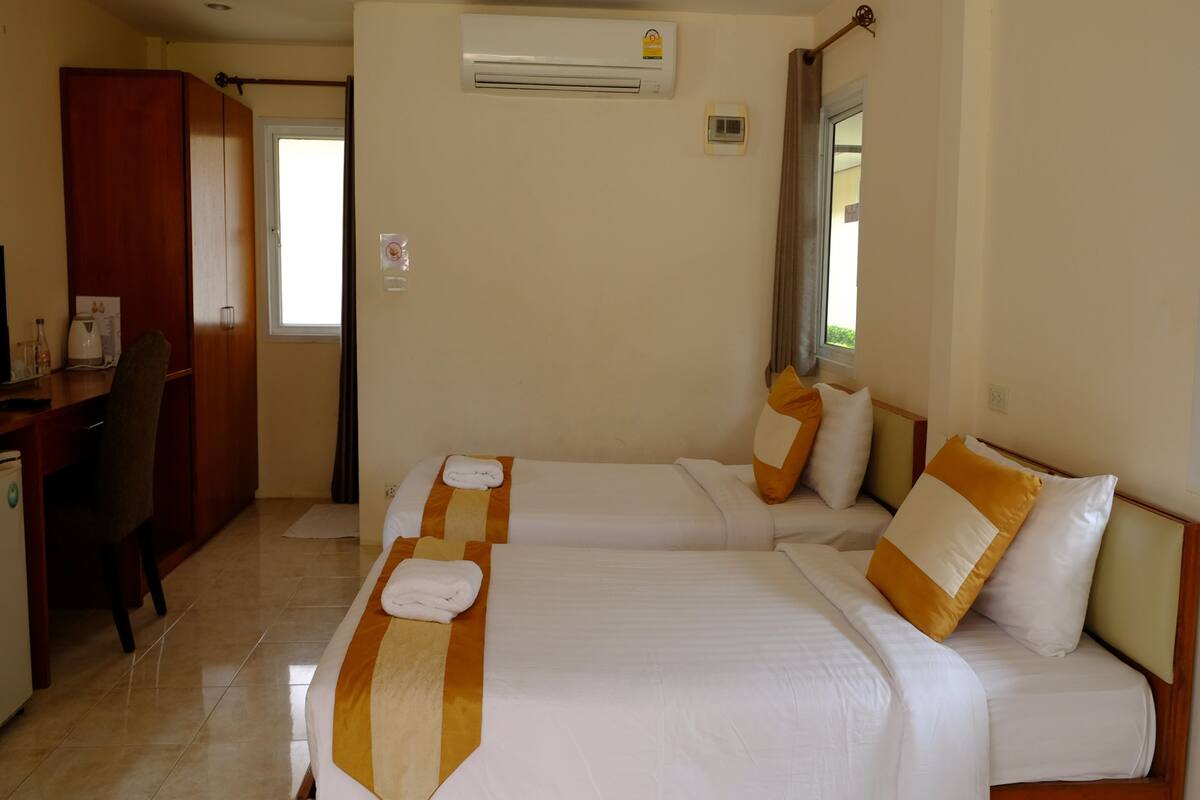 Habitación de hotel con dos camas, un escritorio y un equipo de aire acondicionado.