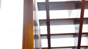 A room with a sloped ceiling, wooden beams, and a window with a view. - Fah Talay Resort (Rayong)