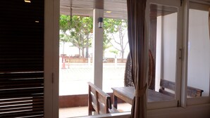 A room with a large window, a wooden bench, and a view of an outdoor area with trees and a fence. - Fah Talay Resort (Rayong)