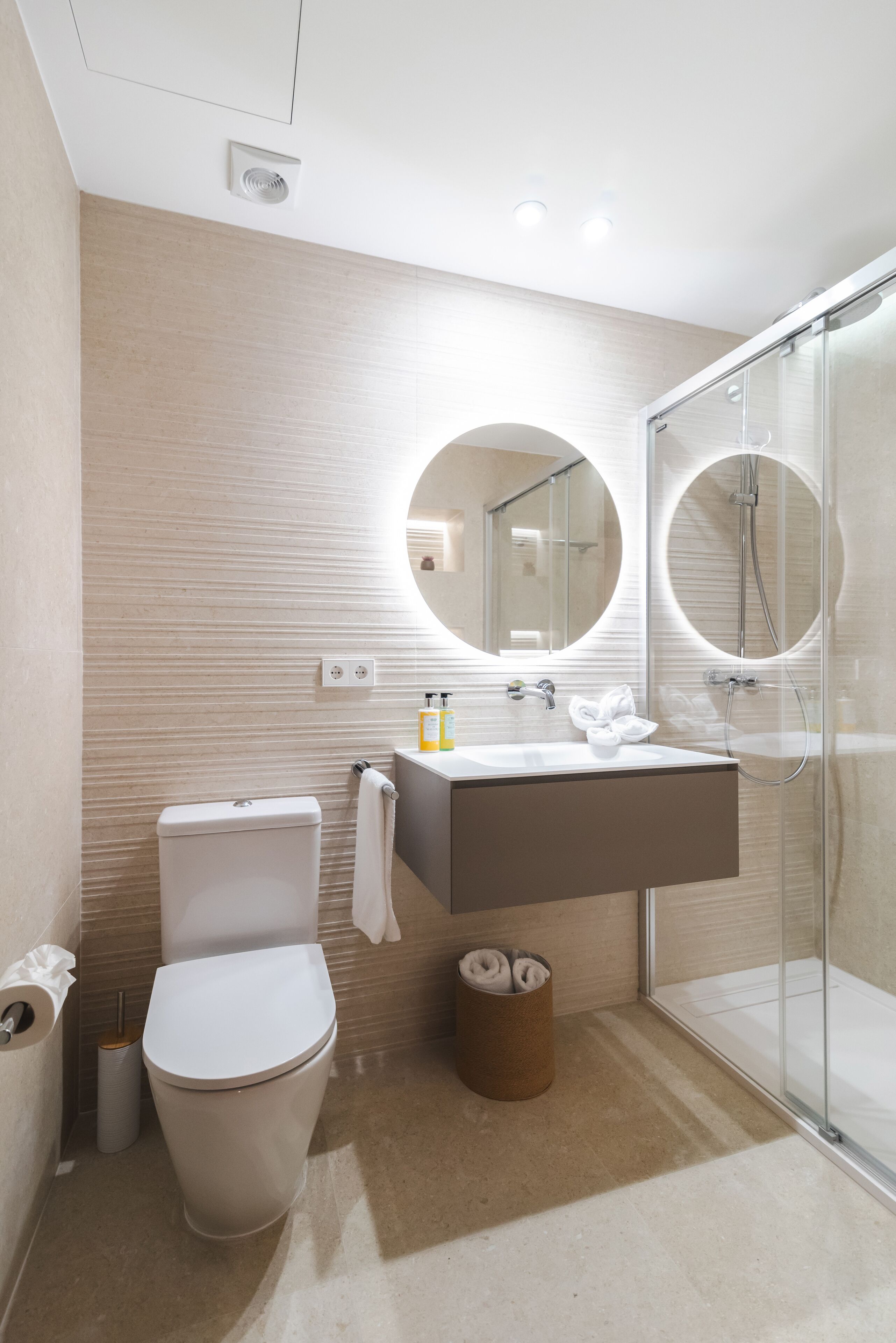 A modern bathroom with a toilet, sink, and glass-enclosed shower.