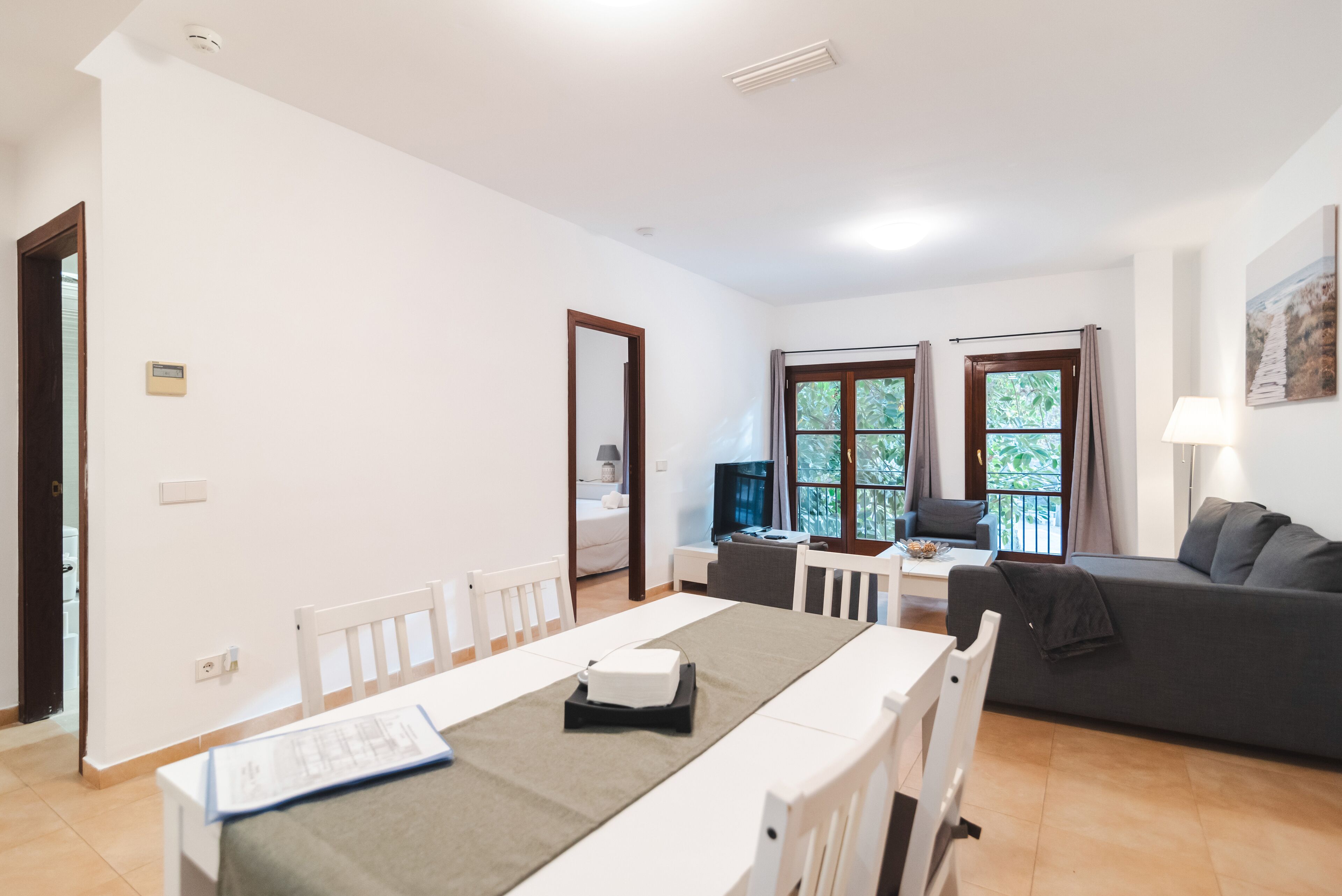 A spacious living area with a dining table, a sofa, and a TV.