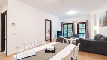 A spacious living area with a dining table, a sofa, and a TV.