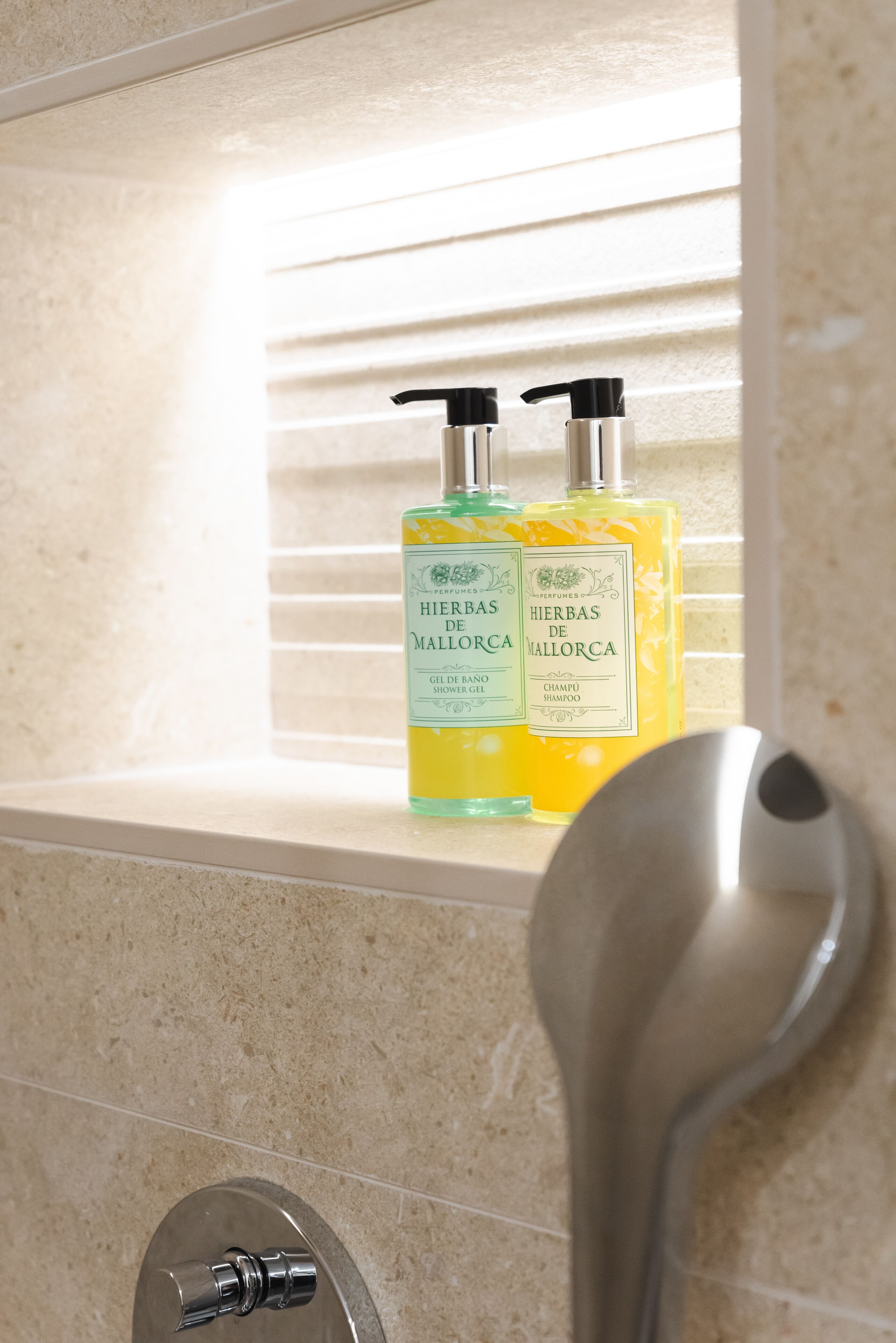 A bathroom with two bottles of 'Hierbas de Mallorca' shampoo and conditioner on a shelf.