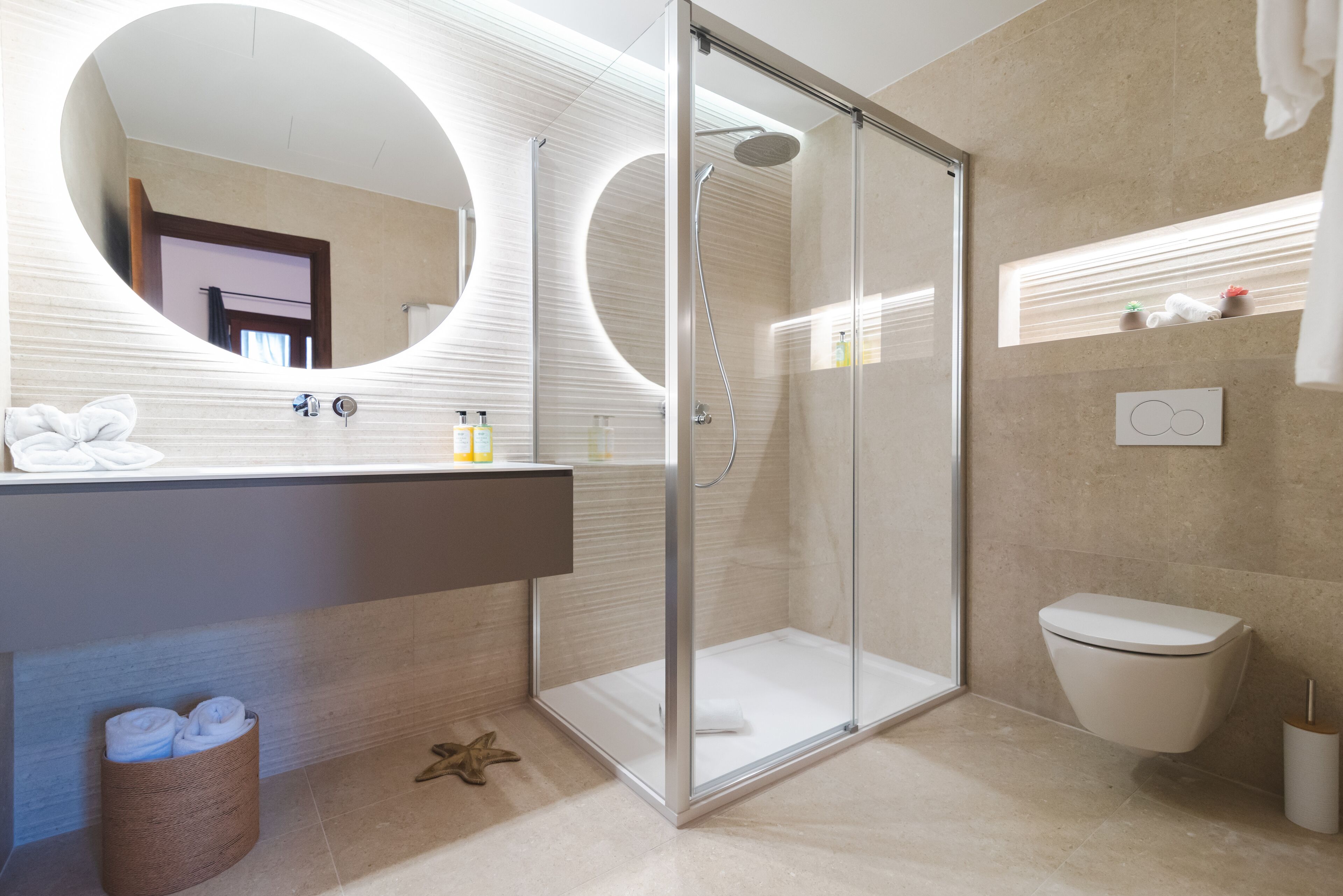 Een moderne badkamer met een douche met glazen wand, een grote spiegel en een toilet.