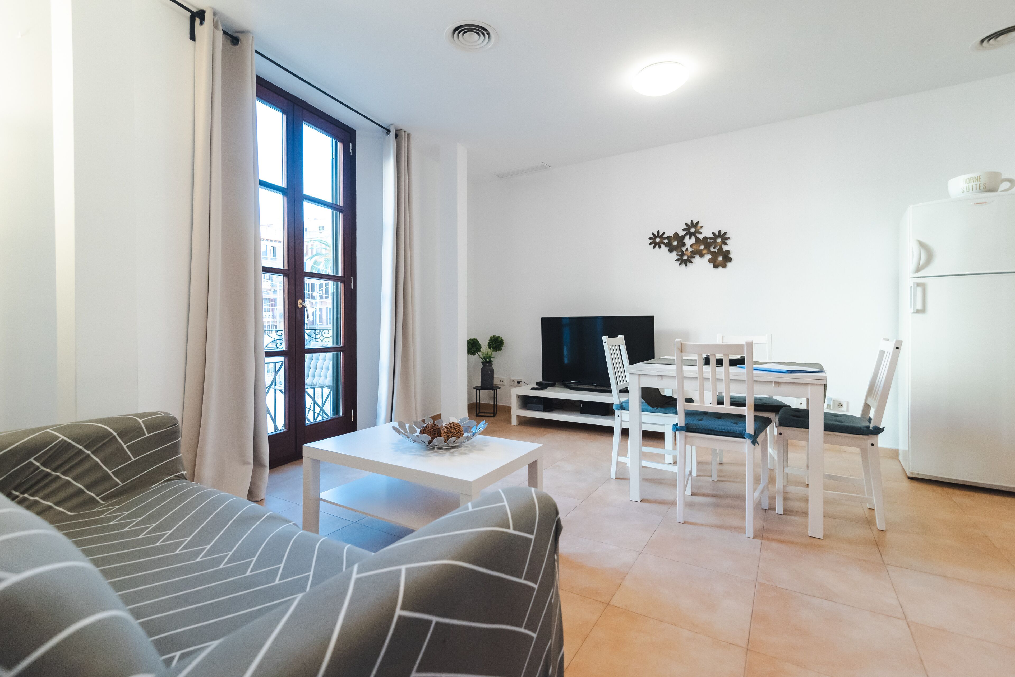 Een moderne woonkamer met een bank, een eettafel met stoelen, een televisie en een koelkast.