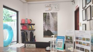 Un área de recepción con un reloj, una pintura de cascada, un folleto de 'Paquetes Turísticos', un cartel que dice 'Mayo' y un código QR.