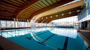 Una piscina interna con soffitto in legno e ampie finestre.