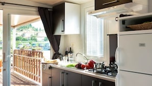 Una cucina compatta con fornello a gas, lavello e frigorifero.