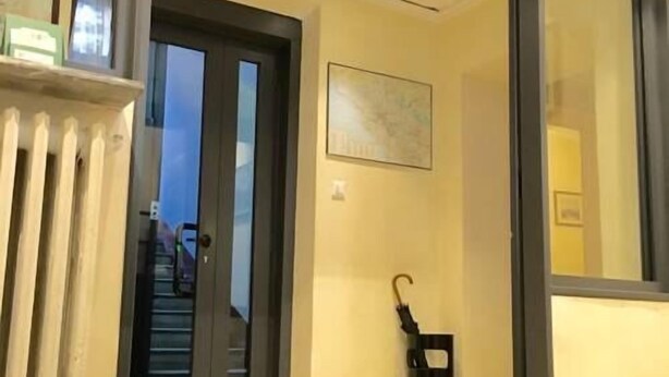 A hotel entrance with a glass door, a framed picture on the wall, and a black umbrella leaning against the wall. - Hotel Fiorenza (Rome)
