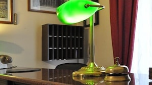 A desk with a green desk lamp, a black filing cabinet, and a brass telephone. - Hotel Fiorenza (Rome)