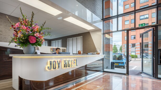 A reception desk with the name "JOY HOTEL" and a large floral arrangement. - Joy Hotel (Amsterdam)