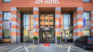 The entrance of the Joy Hotel with a revolving door, a red carpet, and flags. - Joy Hotel (Amsterdam)