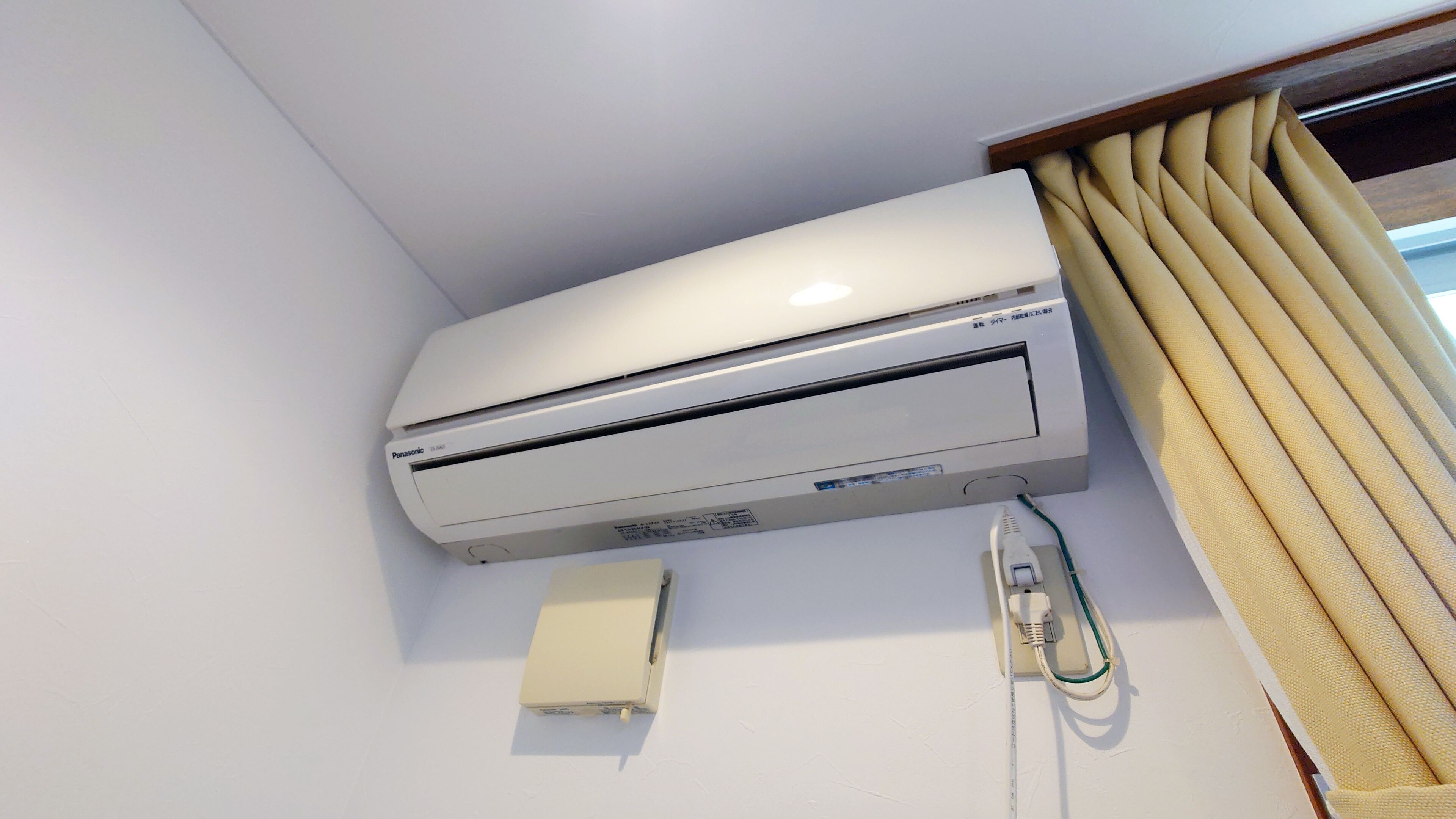 Un equipo de aire acondicionado blanco instalado en una pared, con un enchufe y un cable conectados.