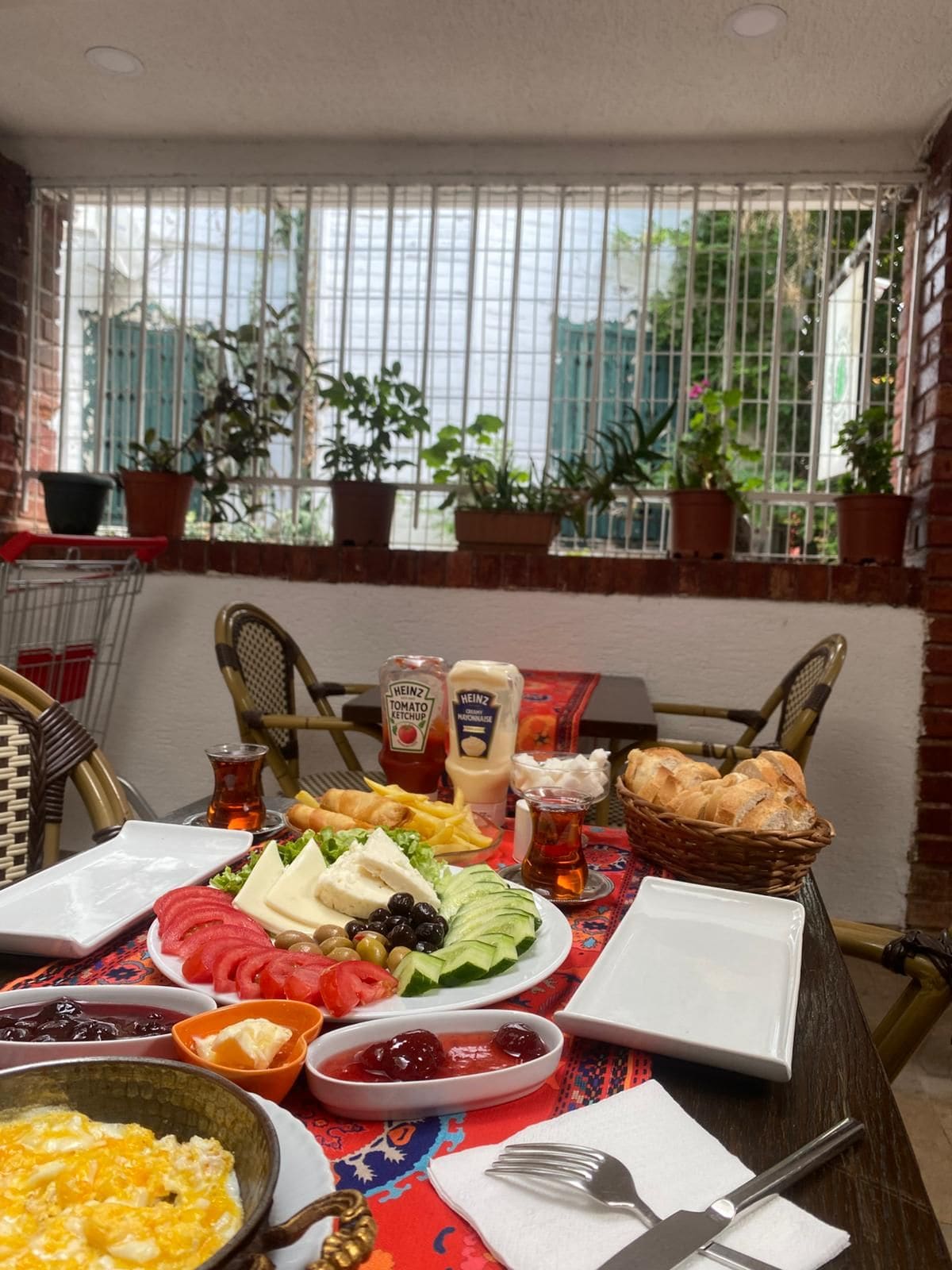Una mesa de comedor dispuesta con diversos alimentos, salsas y vistas al exterior a través de una ventana.