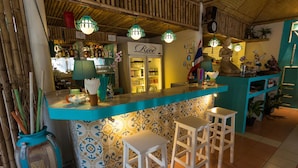 A bar area with a blue counter, white stools, and a patterned wall. - Rice Restaurant & Rooms (Karon)