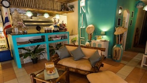 A cozy room with a wooden sofa, a glass coffee table, and a teal accent wall. - Rice Restaurant & Rooms (Karon)