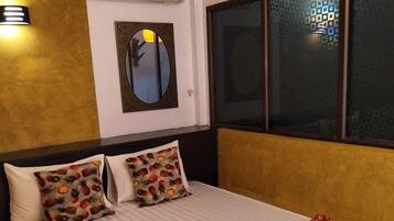 Una habitación de hotel con cama, almohadas, un espejo y ventana con vistas.