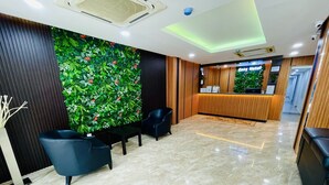 A hotel reception area with a green wall, a reception desk, and seating. - Cozy Hotel at KL Sentral (Kuala Lumpur)