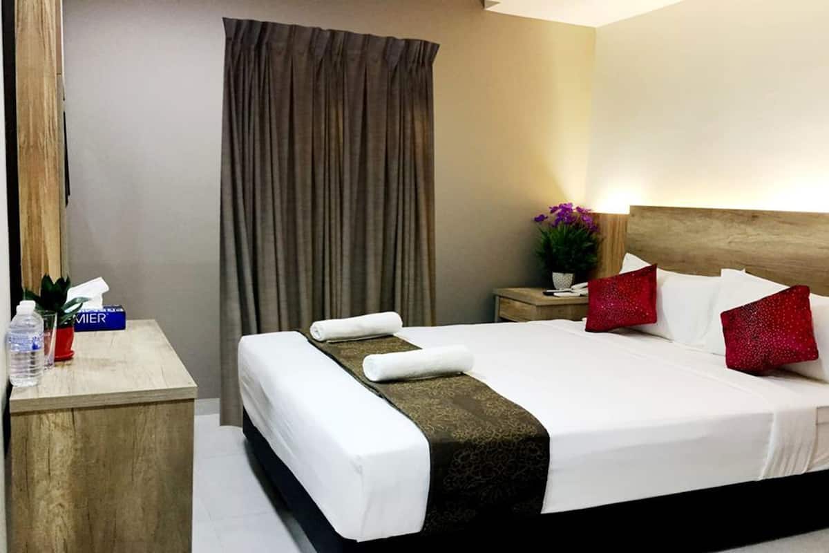 A hotel room with a bed, a nightstand, a desk, a chair, a curtain, and a potted plant.