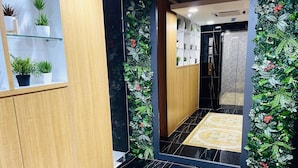 A hallway with a black marble floor, wooden paneling, and a mirrored wall reflecting the space. - Cozy Hotel at KL Sentral (Kuala Lumpur)