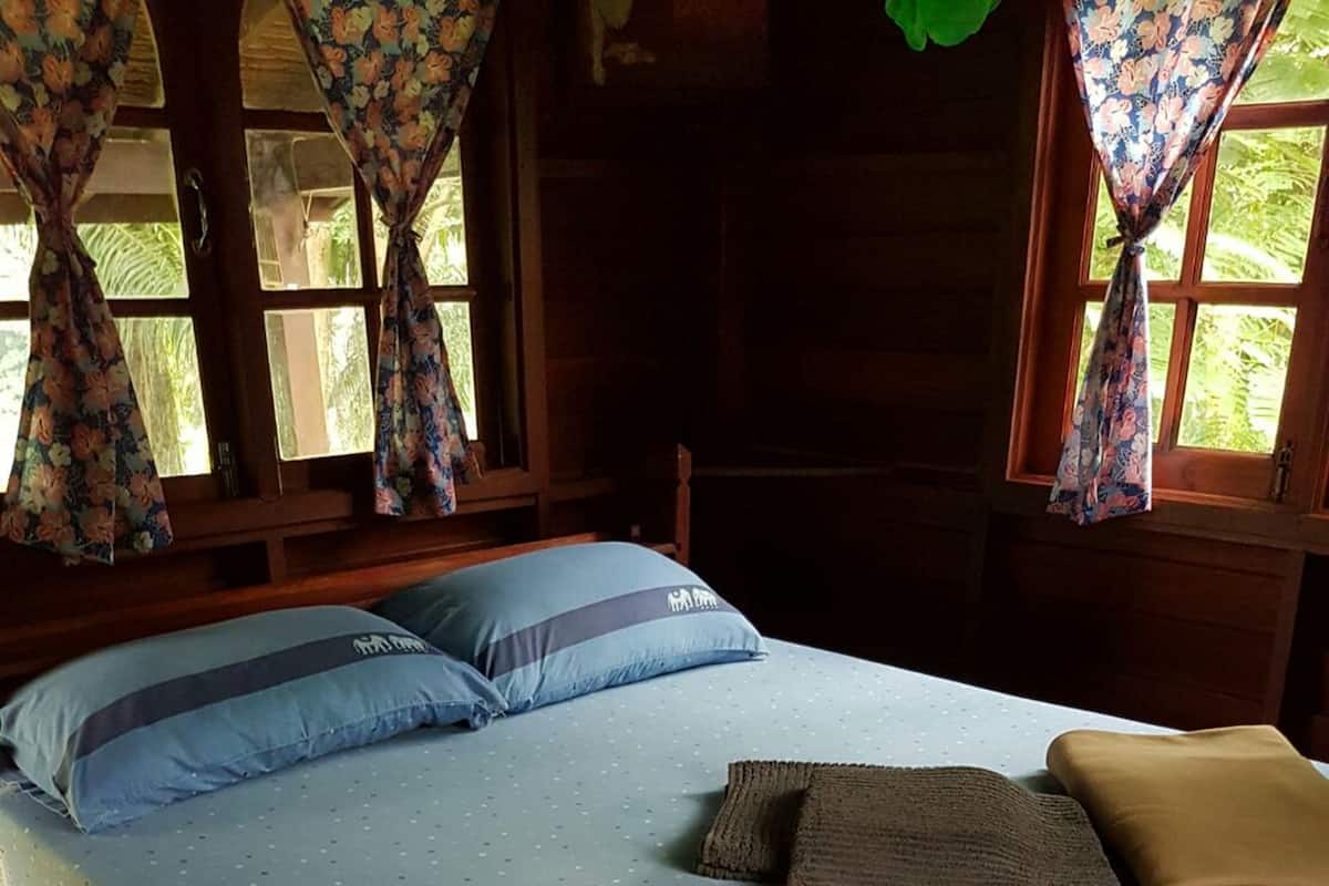 A bed with a blue mattress and pillows, a brown blanket, and a patterned pillowcase.