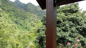 Un balcón de madera con vistas a un paisaje verde exuberante y montañas al fondo.