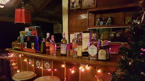 Zona de bar con mostrador de madera, varias botellas de licores y un árbol de Navidad.