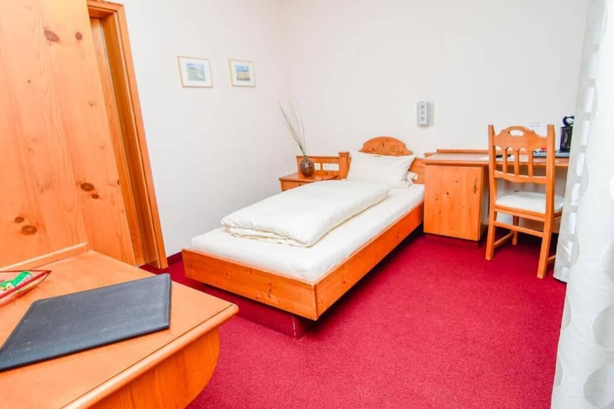 A bedroom with a wooden bed, a desk, and a chair.