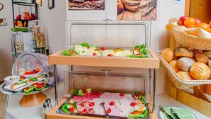 A buffet setup with various food items and a basket of bread. - Gästehaus Engelgasse (Herzogenaurach)