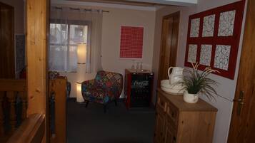 Una sala de estar acogedora con una escalera de madera, un sillón colorido, una máquina expendedora vintage de Coca-Cola y una pared decorada con arte abstracto.