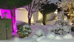 A snow-covered garden with a stone lantern, a wooden bench, and a small tree. - Gästehaus Engelgasse (Herzogenaurach)