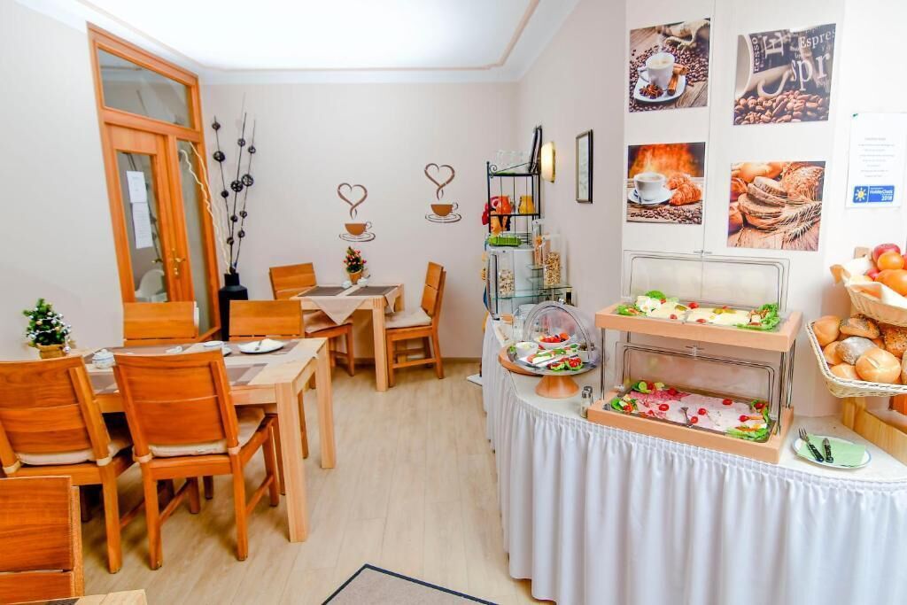Ein Essbereich mit Holzmöbeln, ein Buffet mit verschiedenen Speisen sowie Wanddekorationen mit Kaffee und Gebäck.