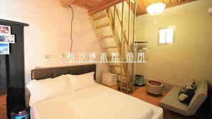A bedroom with a large bed, a wooden ceiling, a small table, and a chair. - O Share Sweet B&B (Jinning)