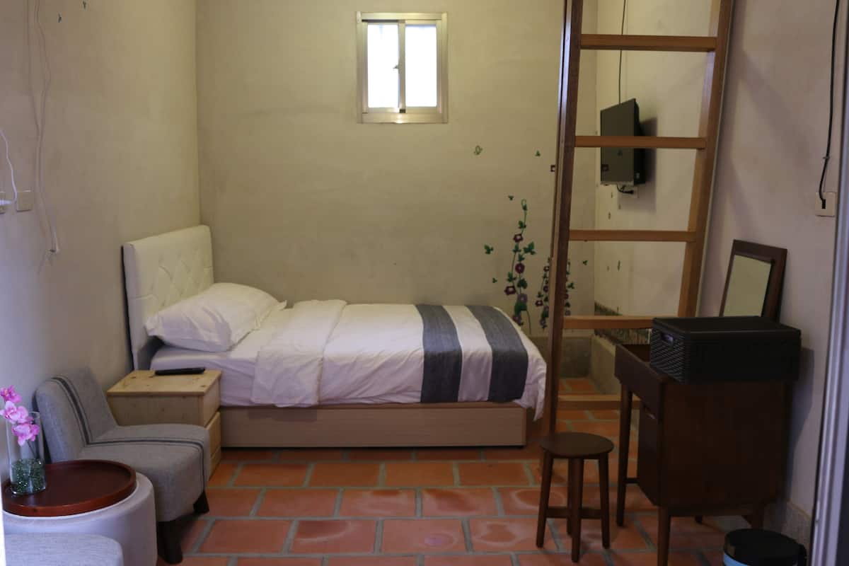 Un dormitorio con una cama, una mesita de noche, una silla, un escritorio y un espejo.