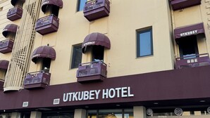 Ein Hotel mit mehreren Balkonen, jeweils mit einem violetten Vordach, auf dem 'UTKUBEY HOTEL' steht.