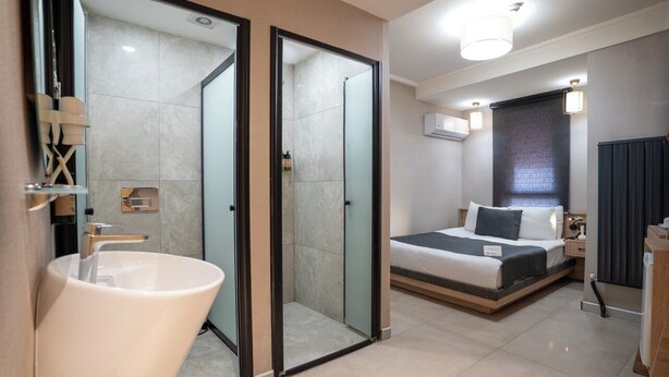 Ein modernes Hotelzimmer mit großem Badezimmer, einem Bett und einem Nachttisch.