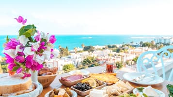 Enjoy a meal with a view of the sea and a coastal town from this beautifully set table.