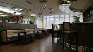 Interior moderno de restaurante con cabinas, mesas altas y asientos de bar.