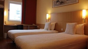 Habitación de hotel con dos camas, un escritorio y una ventana.
