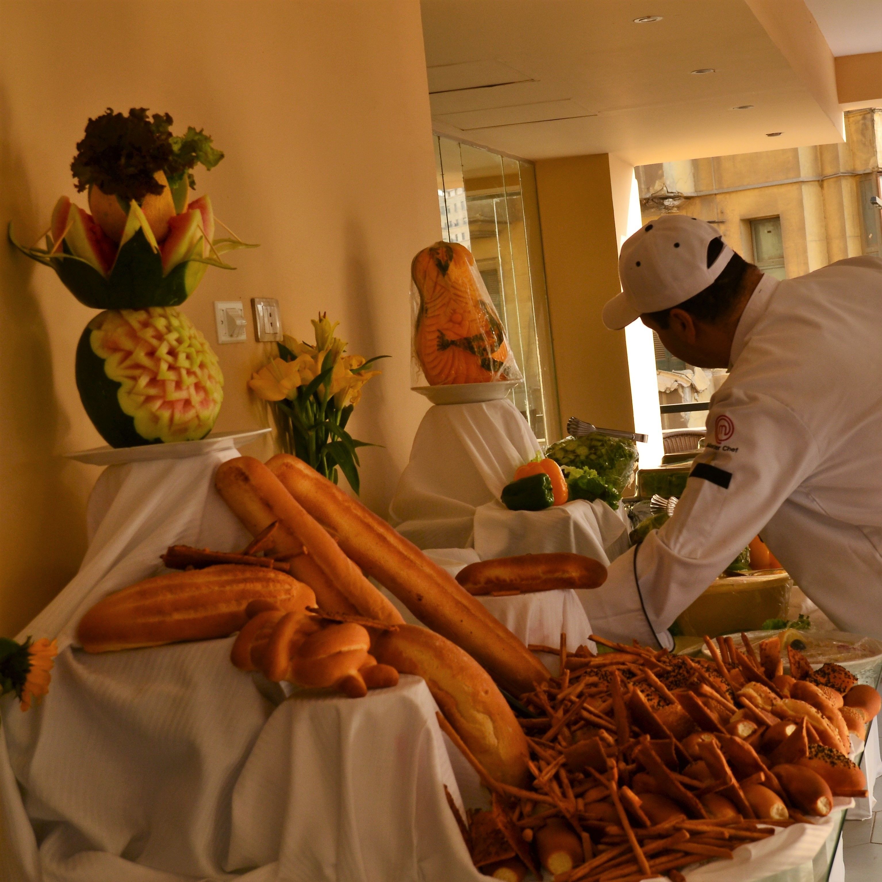 A buffet table with various food items including baguettes and a decorative centerpiece.