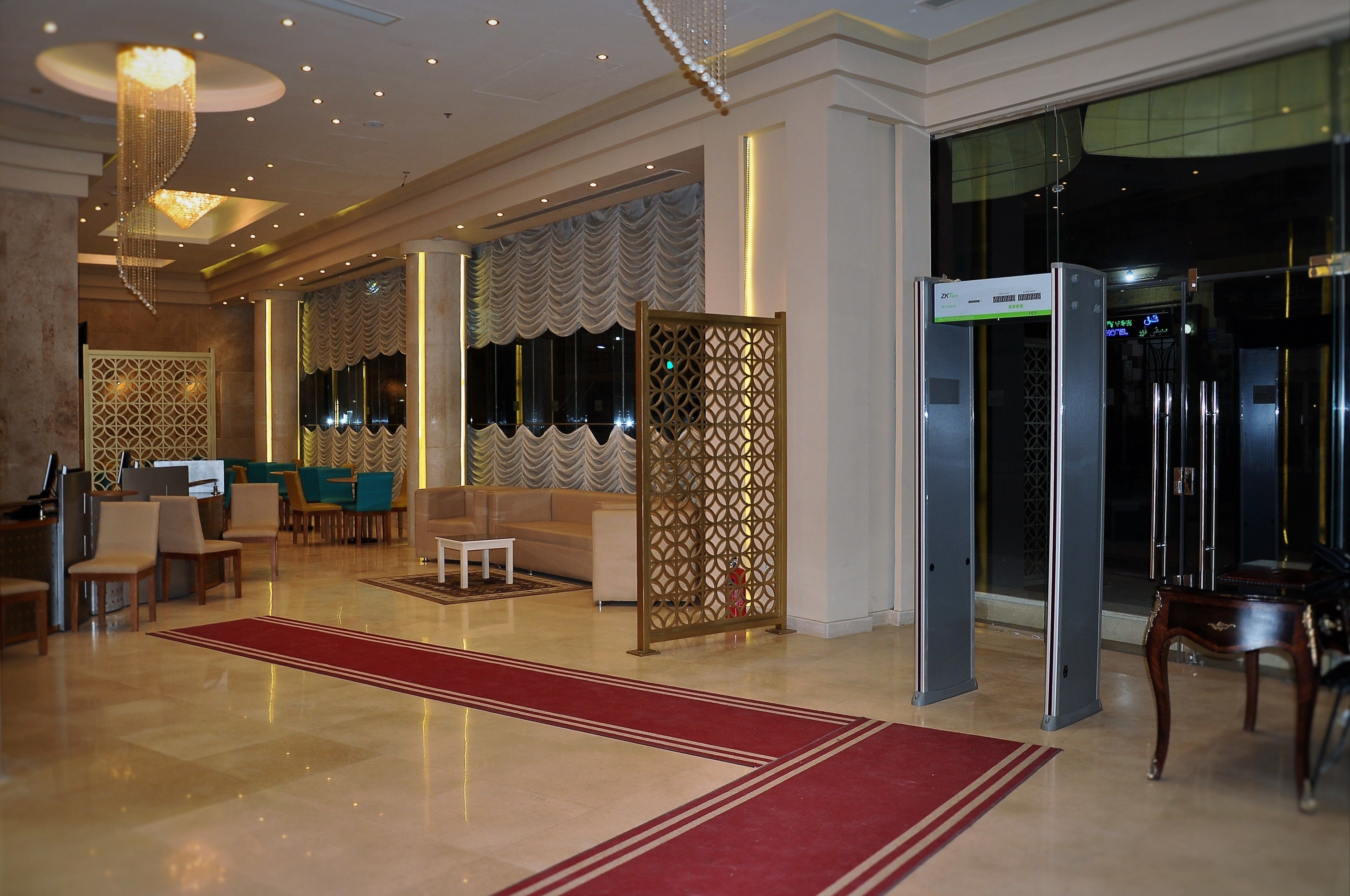 A hotel lobby with a red carpet, seating area, and a reception desk.