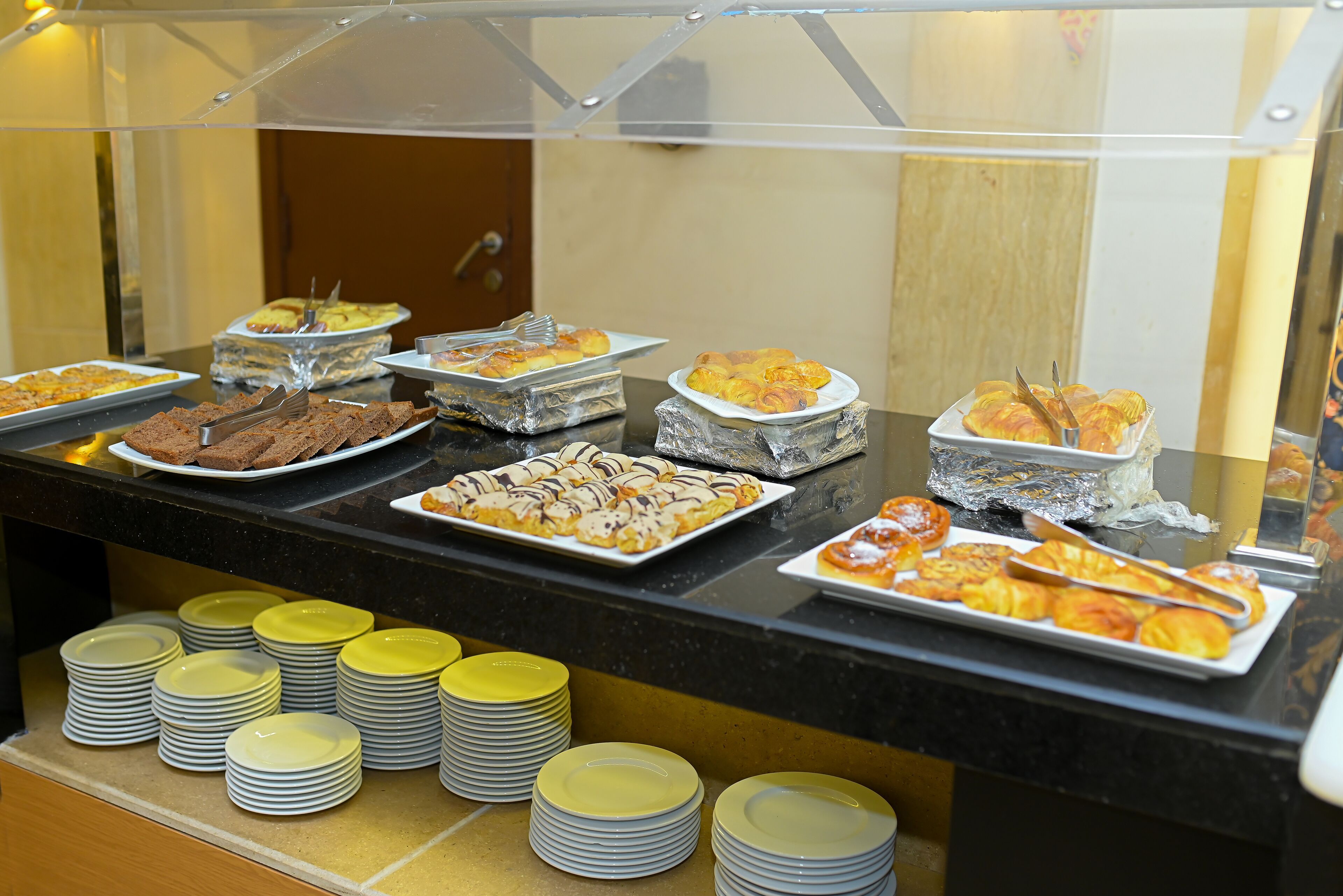 Ein Buffet mit verschiedenen Speisen und gestapelten Tellern.