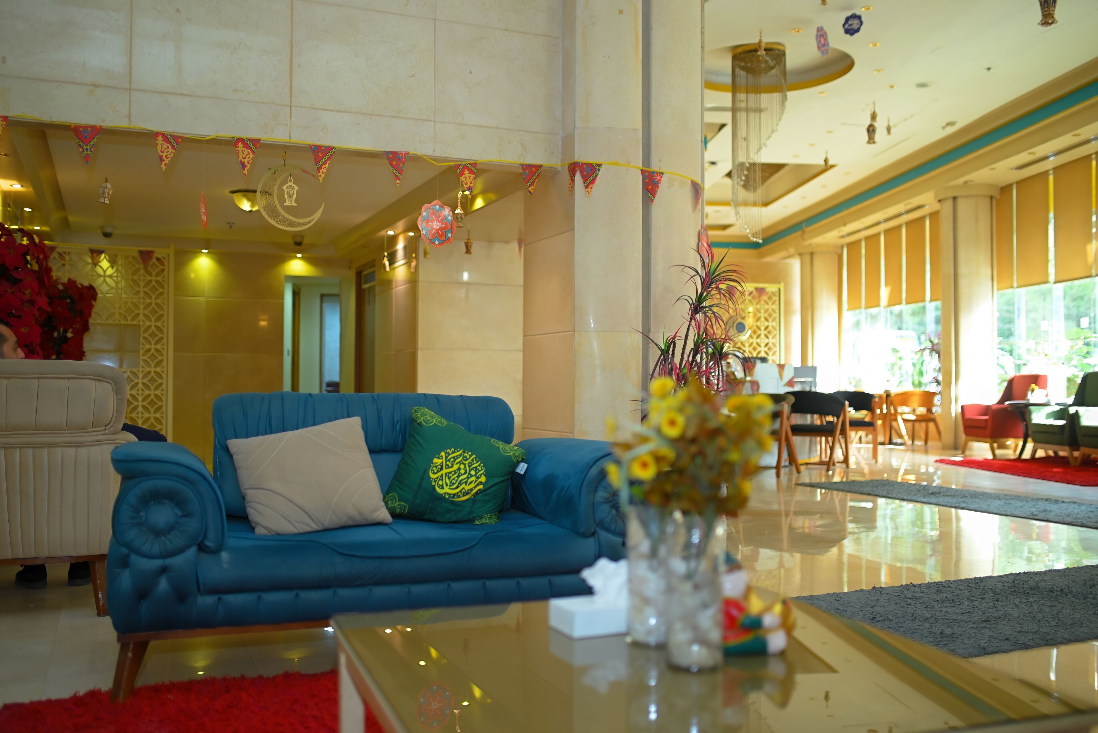 A spacious lobby with a blue sofa, a red rug, and a vase of flowers.